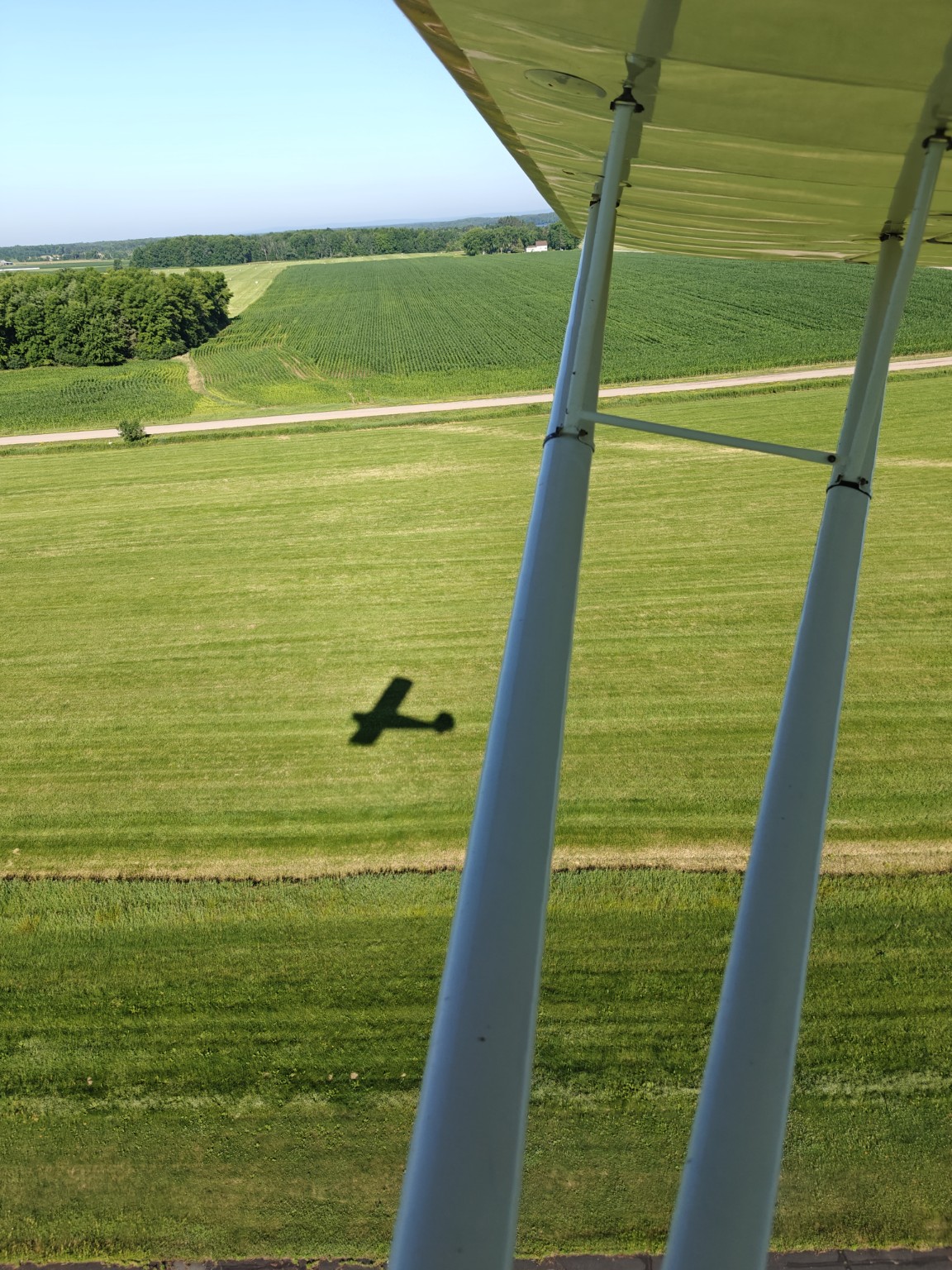 The shadow of a small airplane crossing a green field during a low approach